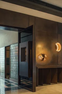 Hotel lobby with tile walls, a doorway leading to another room, a clock on the wall, and a modern atmosphere