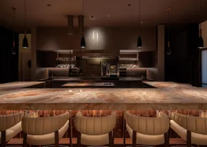 Sophisticated kitchen with a marble countertop, wooden chairs, and stainless steel appliances, featuring wine glasses and a dining table