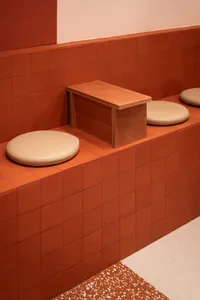 Warm and inviting bathroom with orange tiles, two toilets, and two benches, creating a cozy atmosphere