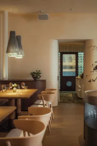 Warm and inviting restaurant interior with dining area, bar, and wine glasses, featuring a comfortable atmosphere for guests