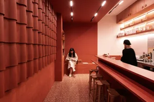 A warm and inviting restaurant interior with red walls, chairs, and a dining table, perfect for socializing or relaxing over a meal or drink