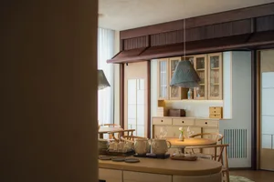Warm kitchen with wooden cabinets, white countertops, and appliances, surrounded by chairs and a dining table