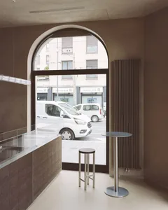 Cozy urban cafe with a dining table, chairs, and a window allowing natural light, set against a backdrop of concrete walls and a modern atmosphere