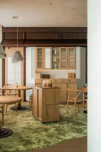 Cozy restaurant interior with wooden floors and walls, featuring dining tables, chairs, bottles, and wine glasses