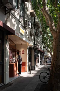 A bustling Asian city street with a mix of traditional and modern architecture, featuring wooden doors and balconies, and lively street activity