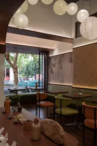 Cozy cafe interior with wooden floors and tables, plush chairs, and a potted plant adding to the ambiance