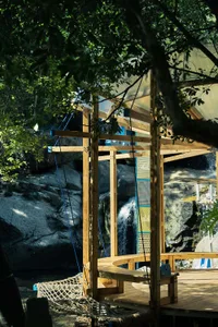 A wooden cabin with a hanging swing in a park or recreational area, featuring a relaxing and enjoyable environment