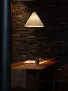 A darkened dining space with a wooden table and chairs, a vase with flowers, and a book, creating a warm and inviting atmosphere