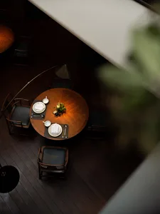 A warm and inviting dining area with a large wooden table surrounded by chairs, vases, and various tableware