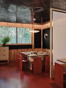 A modern black and white dining area with wooden tables and chairs, featuring bowls for serving food