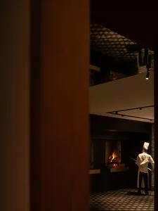 A quiet kitchen scene with a man standing in front of an open fireplace, surrounded by a warm and inviting atmosphere