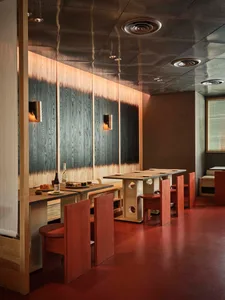 Cozy restaurant interior with wooden walls and floors, tables, chairs, and wine glasses, creating a warm and inviting atmosphere