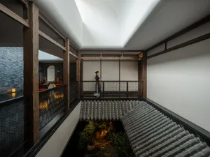 寧靜的亞洲風格建築，一位女子站在陽台上俯瞰花園，周圍環繞盆栽植物與裝飾花瓶