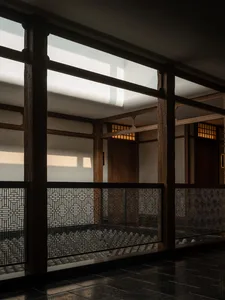 A serene Asian-style hallway with a wooden floor, a staircase, and a bench, set against a backdrop of elegant architecture