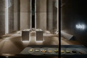 An empty room with a large window, several small tables with bowls of food, and a clean, well-lit atmosphere