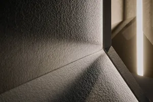 A concrete wall with a reflection of a window on its surface, showing a textured appearance