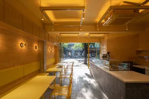 Warm and inviting restaurant interior with yellow walls, dining tables, and chairs, featuring umbrellas for outdoor dining