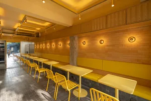 Warm and inviting restaurant interior with yellow walls, dining tables, and matching chairs, featuring well-designed lighting