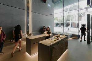 現代商店內部，設有櫃檯區、石材與玻璃牆面及裝飾元素，搭配人物與溫暖燈光