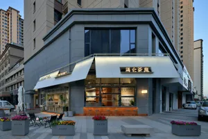 A modern Asian restaurant with a large window, gray and white elements, chairs, and potted plants, creating a clean and inviting atmosphere