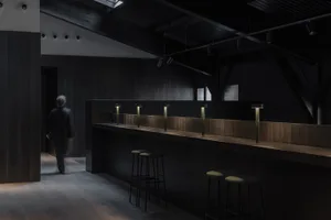 A modern bar area with a well-lit countertop and stools, creating a welcoming atmosphere