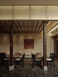 Cozy restaurant interior with wooden beams, dim lighting, and wine glasses on tables