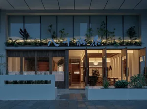 Modern Asian restaurant with a glass door, wooden furniture, and metal accents, featuring a stylish and elegant atmosphere