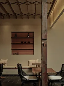 A warm and inviting living area with a dining table, couch, and bookshelf, featuring wooden elements and multiple decorative bottles