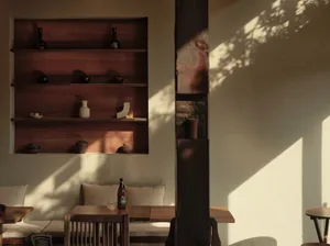 Cozy living area with wooden walls and floors, featuring a dining table and chairs, decorative vases, and a bottle