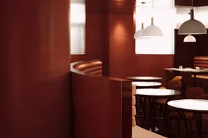 A warm and inviting dining space with multiple tables and chairs, red walls, and natural light from windows