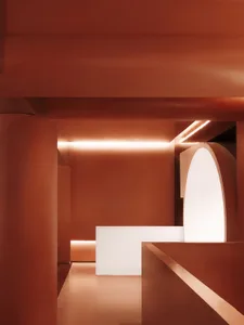 A modern museum interior with a white countertop, red walls, and two pillars, creating a warm and classic atmosphere
