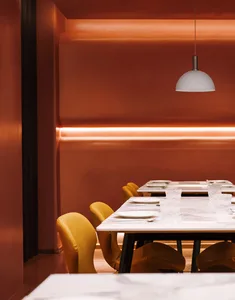 A warm and inviting dining area with a long wooden table surrounded by chairs, set with wine glasses, suggesting a comfortable space for socializing and meals