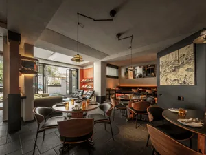 Cozy cafe with multiple tables, couches, and comfortable seating, featuring wine glasses, cups, bowls, and vases