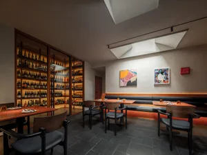 Dining area with tables, chairs, and wine bottles, creating an inviting atmosphere for patrons