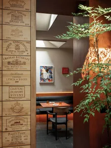 A dining area with tables and chairs, surrounded by wine bottles on the walls, creating a sophisticated ambiance