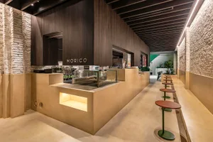 Inviting cafe with a counter, display case, and wooden elements, featuring chairs and a warm atmosphere
