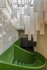 A museum staircase with white walls, green steps, and hanging white curtains creating a unique atmosphere with a sense of mystery or artistic expression