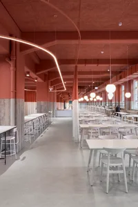 A warm and inviting dining space with red walls and ceilings, featuring multiple tables and chairs, lamps, and well-lit ambiance