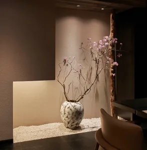 A cozy living space with a stone vase, two chairs, and a dining table, creating a warm atmosphere