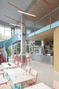Modern restaurant interior with a large open area, bar, and dining tables, featuring comfortable seating and a warm atmosphere