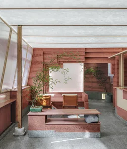 Open modern living area with a red interior design theme, featuring two couches, a dining table, chairs, and a potted plant, with a focus on comfort and functionality