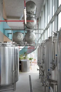 Industrial space with metal tanks, pipes, and a chair, featuring a mix of real and rendered elements