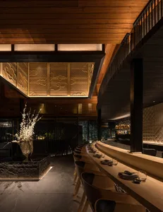 Warm and inviting restaurant interior with wooden floors and walls, featuring dining tables and chairs, and wine glasses on some tables