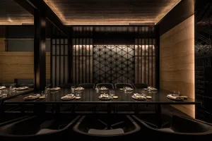 Formal dining space with a large black table and multiple chairs, set up for a meal with a formal atmosphere