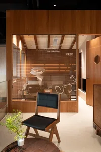 Modern living room with wooden floors and walls, featuring a dining table, two chairs, and a potted plant