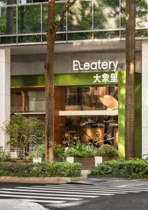 設計精良的亞洲餐廳，擁有綠色立面、自然光線與盆栽，設有桌椅的用餐區