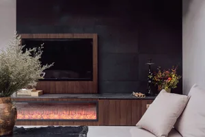 Modern living room with a flat screen TV, wooden furniture, a black fireplace, and inviting atmosphere
