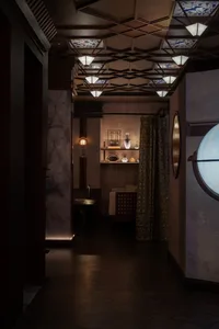Cozy modern living space with dim lighting, wood, and stone elements, featuring a round window, couches, and decorative vases
