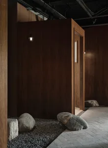 Dark wood-panelled bathroom with a doorway and two large rocks in front, creating a calm and serene atmosphere