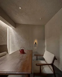 Dimly lit living space with a dining table, chairs, and cement block walls, creating a cozy and modern atmosphere